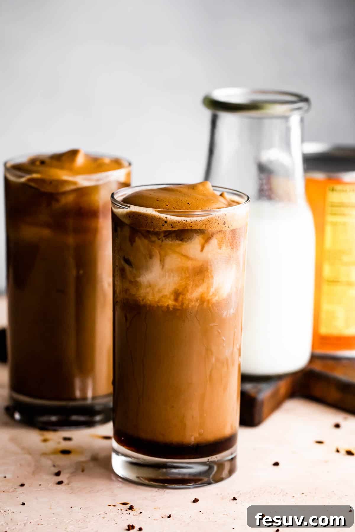Starbucks Inspired Pumpkin Cream Cold Brew 6 Two glasses of Pumpkin Cream Cold Brew, with a milk bottle and decorative pumpkins in the background.