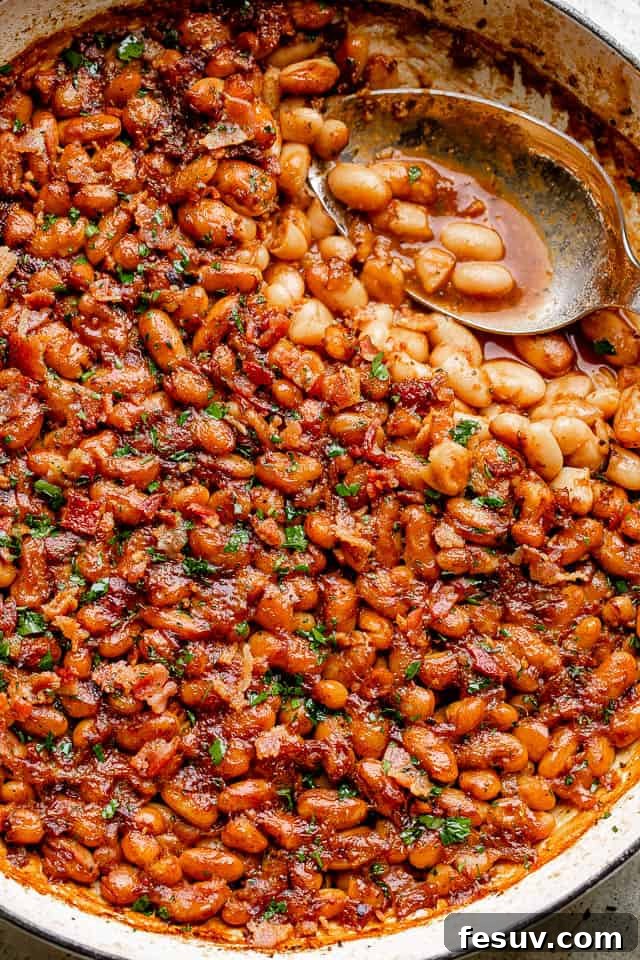 Experience the extraordinary with these homemade maple bacon baked beans, featuring a sweet, tangy, and subtly spicy profile, highlighted by root beer! A rustic pot filled with rich, homemade maple bacon baked beans, garnished with fresh parsley and crispy bacon bits.