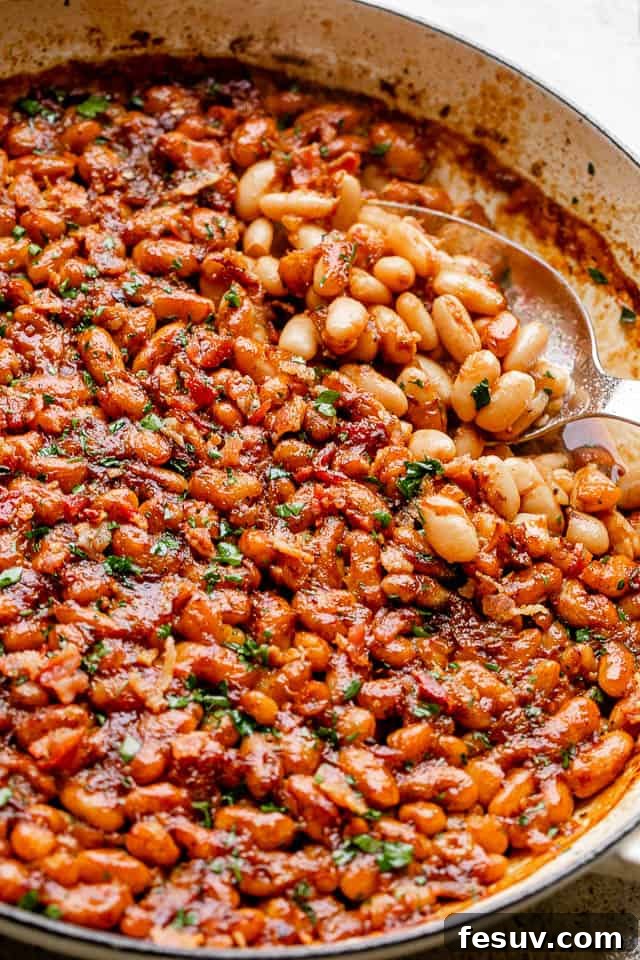 Scooping out delicious homemade baked beans, a perfect blend of sweet, tangy, and spicy flavors. A serving spoon lifting a generous portion of maple bacon baked beans from a pot, showcasing the rich sauce and tender beans.