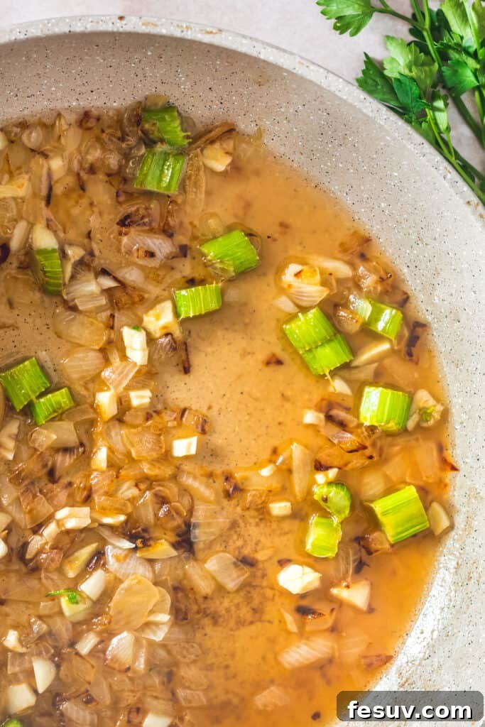A ceramic skillet with a mixture of chopped vegetables and wine.