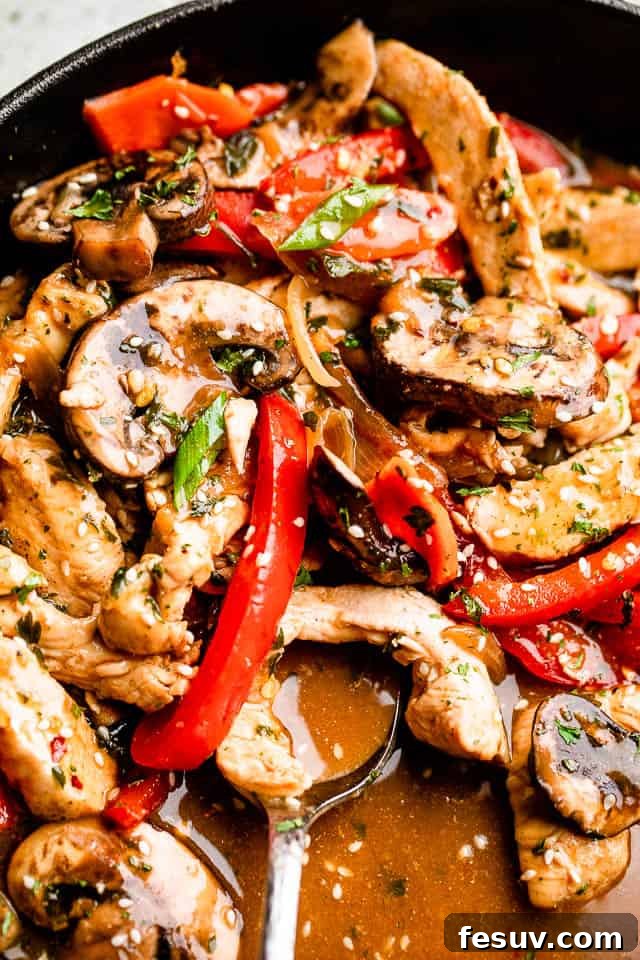 This better than takeout chicken stir fry recipe is packed full of fresh veggies and covered in a flavor-packed garlic and ginger sauce. Close-up of cooked chicken, mushrooms, and red bell peppers glistening in a wok