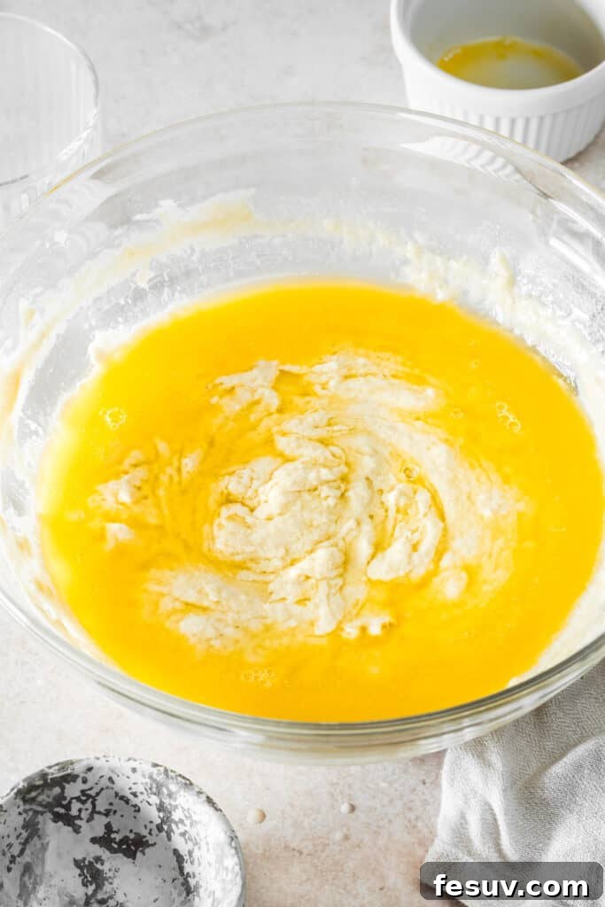 Buttery Homemade Crescent Rolls 6 A mixing bowl with soft dough and a pool of melted butter inside, ready to be incorporated.