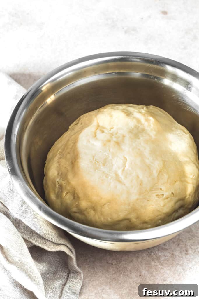 Buttery Homemade Crescent Rolls 7 A stainless steel mixing bowl holding a perfectly smooth, soft ball of risen dough.