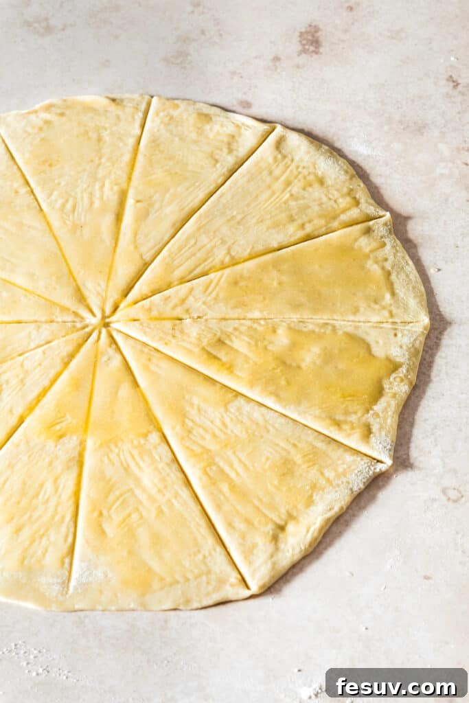 Buttery Homemade Crescent Rolls 8 Dough rolled into a perfect circle and cut into wedges, lightly brushed with butter, ready for shaping.