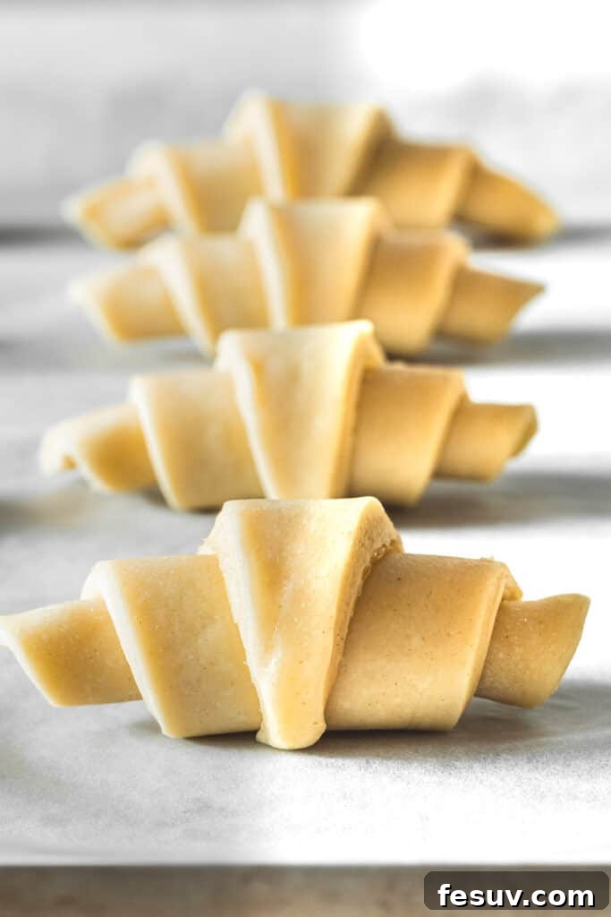 Buttery Homemade Crescent Rolls 9 Raw dough crescents neatly arranged on a parchment-lined baking sheet, preparing for their second rise.