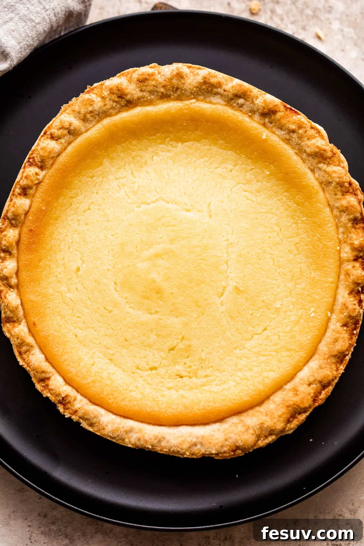 overhead shot of homemade buttermilk pie set on a black plate.