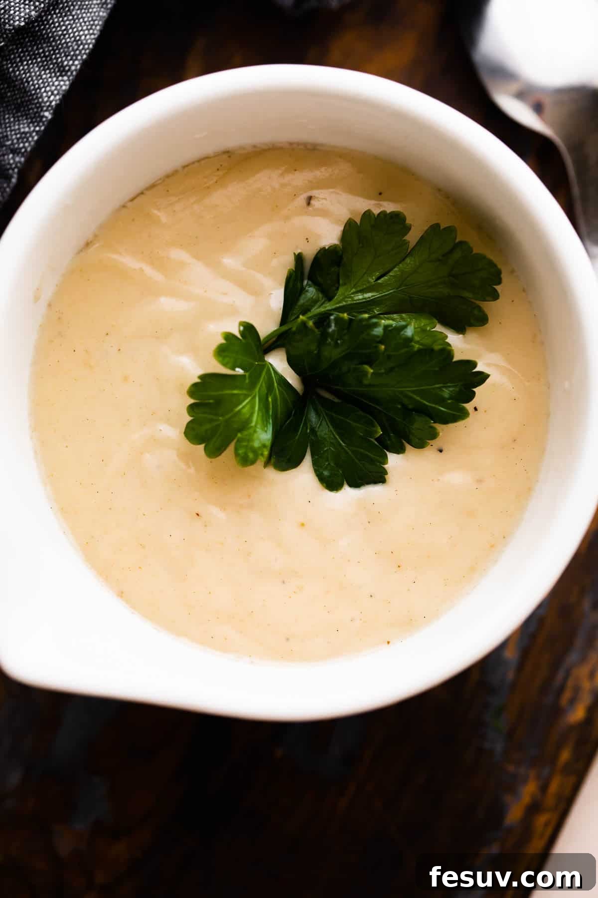 overhead shot of a white ceramic cup filled with homemade cream of chicken soup