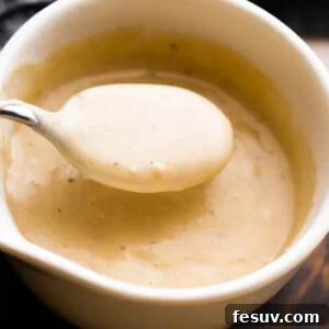 overhead shot of a white ceramic cup filled with homemade cream of chicken soup and a spoon scooping out the soup.
