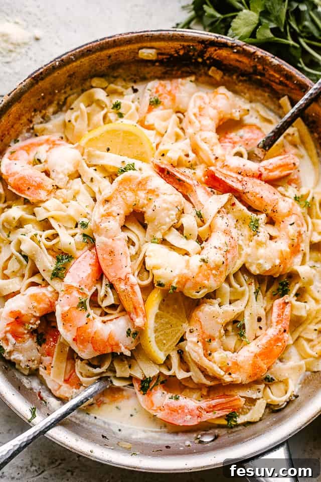 Serve up this incredible Shrimp Alfredo Pasta tonight! Creamy Shrimp Alfredo Pasta with serving spoons ready to be eaten