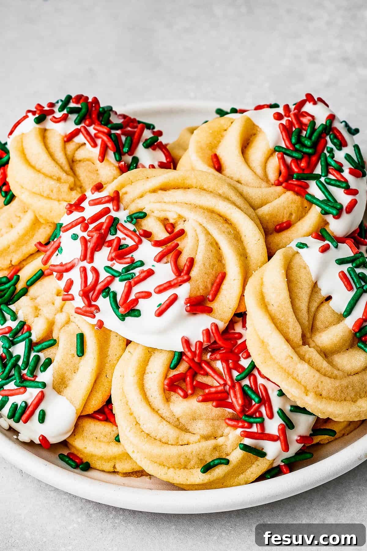 Butter cookies decorated with white chocolate and red and green sprinkles.
