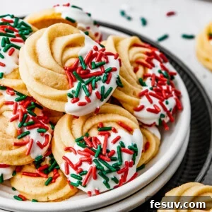 A small dessert plate stacked on top of several other plates, and piled with iced butter cookies.