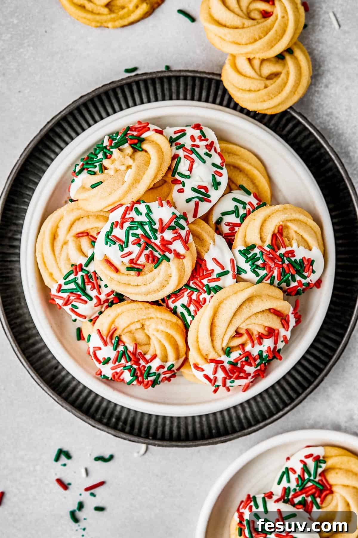 overhead shot of a small dessert plate stacked on top of several other plates, and piled with iced butter cookies.
