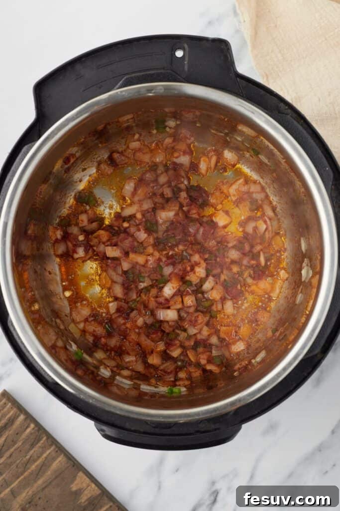 Overhead shot of an Instant Pot with sautéed vegetables, tomato paste, and spices fragrant and combining.