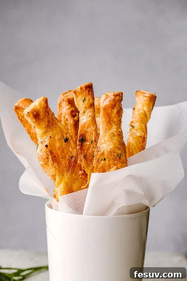 These cheese sticks are addictive movie snacks and great party food ideas! Crunchy puff pastry, melty cheesy and your favorite spices - YUM! Puff Pastry sticks ready to serve in a white cup.