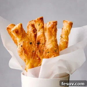 Golden Flaky Cheese Twists 2 Puff Pastry sticks ready to serve in a white cup.