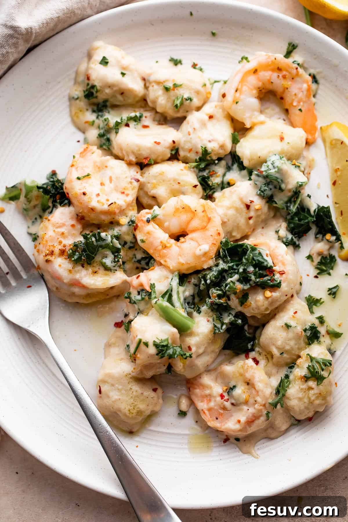 Velvet Parmesan Gnocchi with Succulent Shrimp 7 overhead shot of creamy gnocchi with shrimp served on a white plate with a fork placed to the left side on the plate.