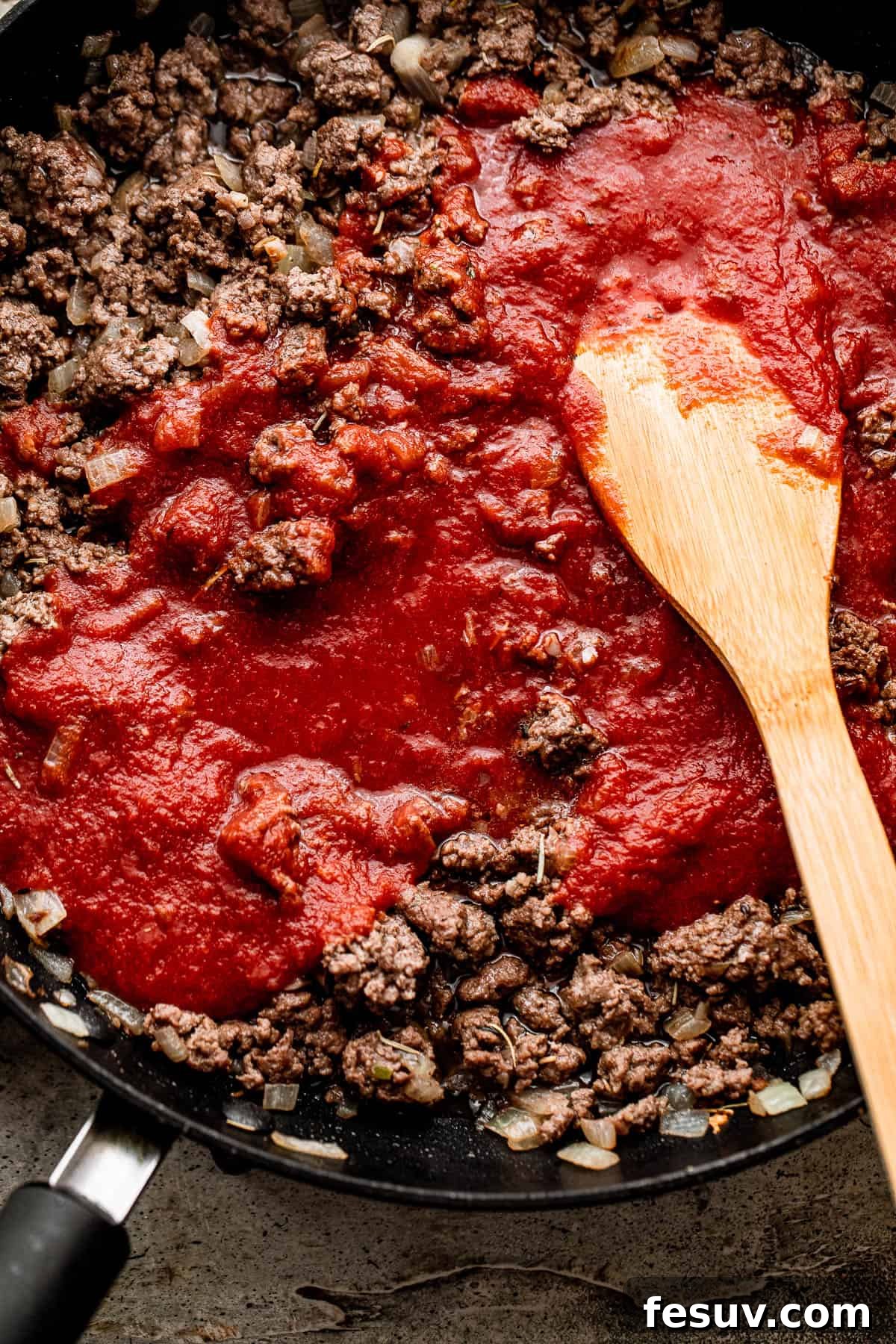 Low and Slow Lasagna Feast 4 cooking ground beef with tomato sauce in a skillet.