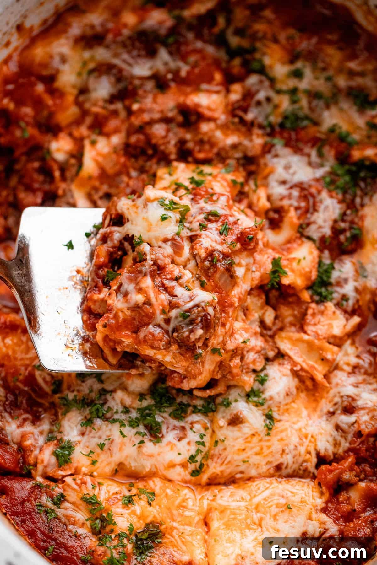 Low and Slow Lasagna Feast 6 up close shot of a spatula lifting up a piece of lasagna from the slow cooker.