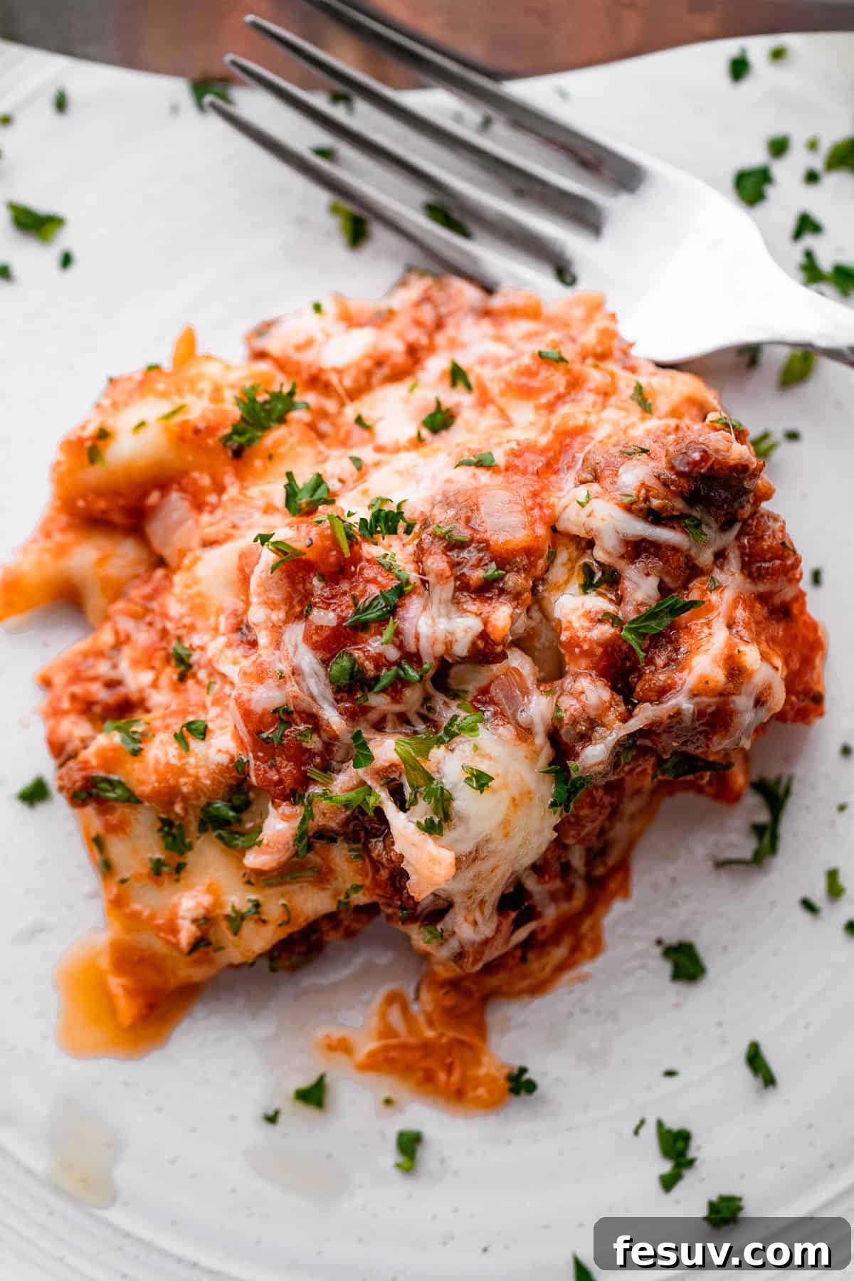 Low and Slow Lasagna Feast 7 piece of lasagna served on a white plate with a fork placed to the side of it.