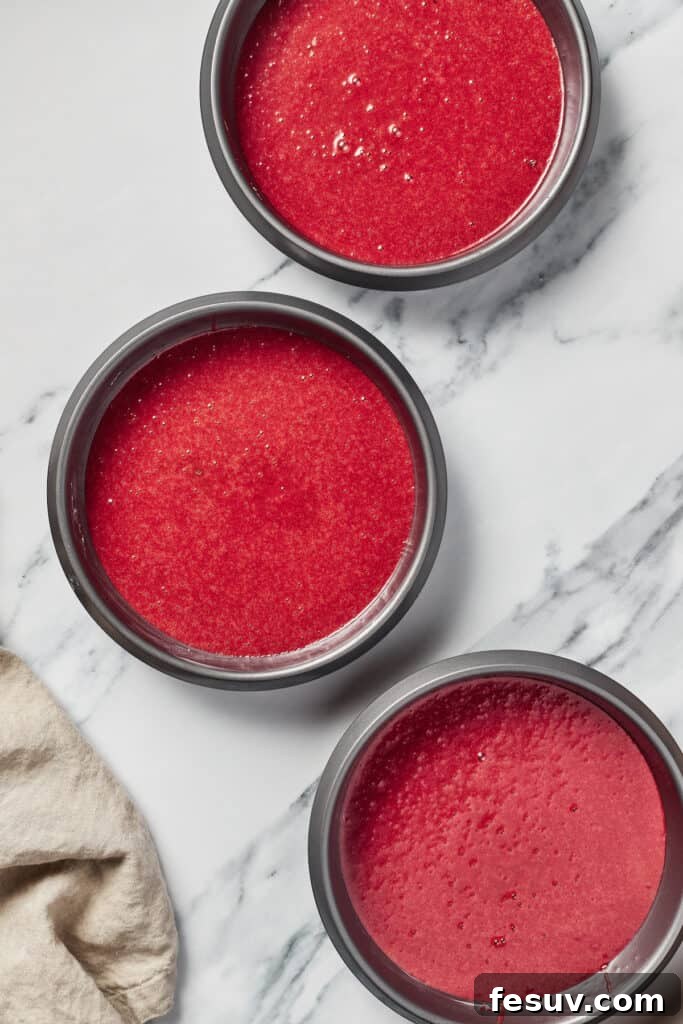 Three perfectly baked, cooled red velvet cake layers arranged on a marble work surface, ready for frosting.
