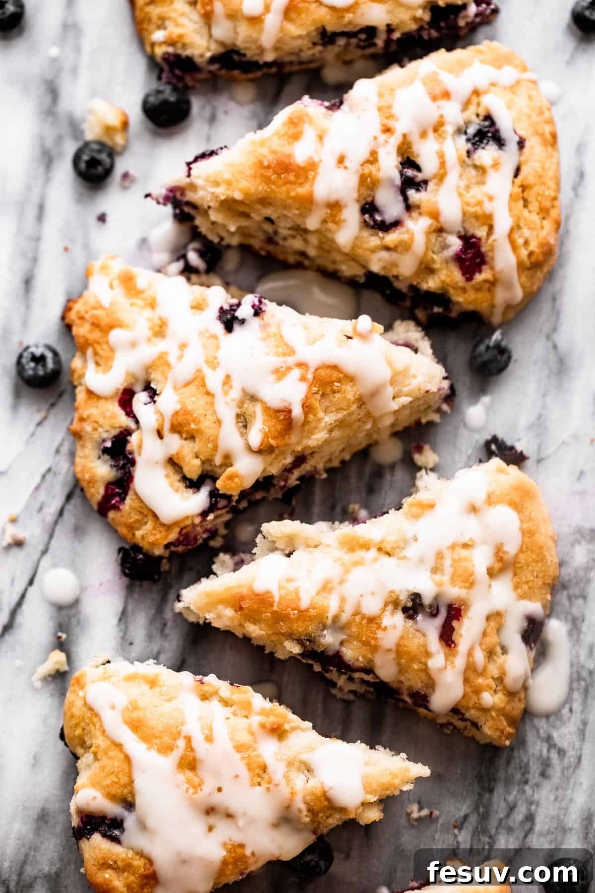 Moist and easy Blueberry Scones made with wholesome ingredients. overhead shot of blueberry scones arranged in a row on top of a marble slab