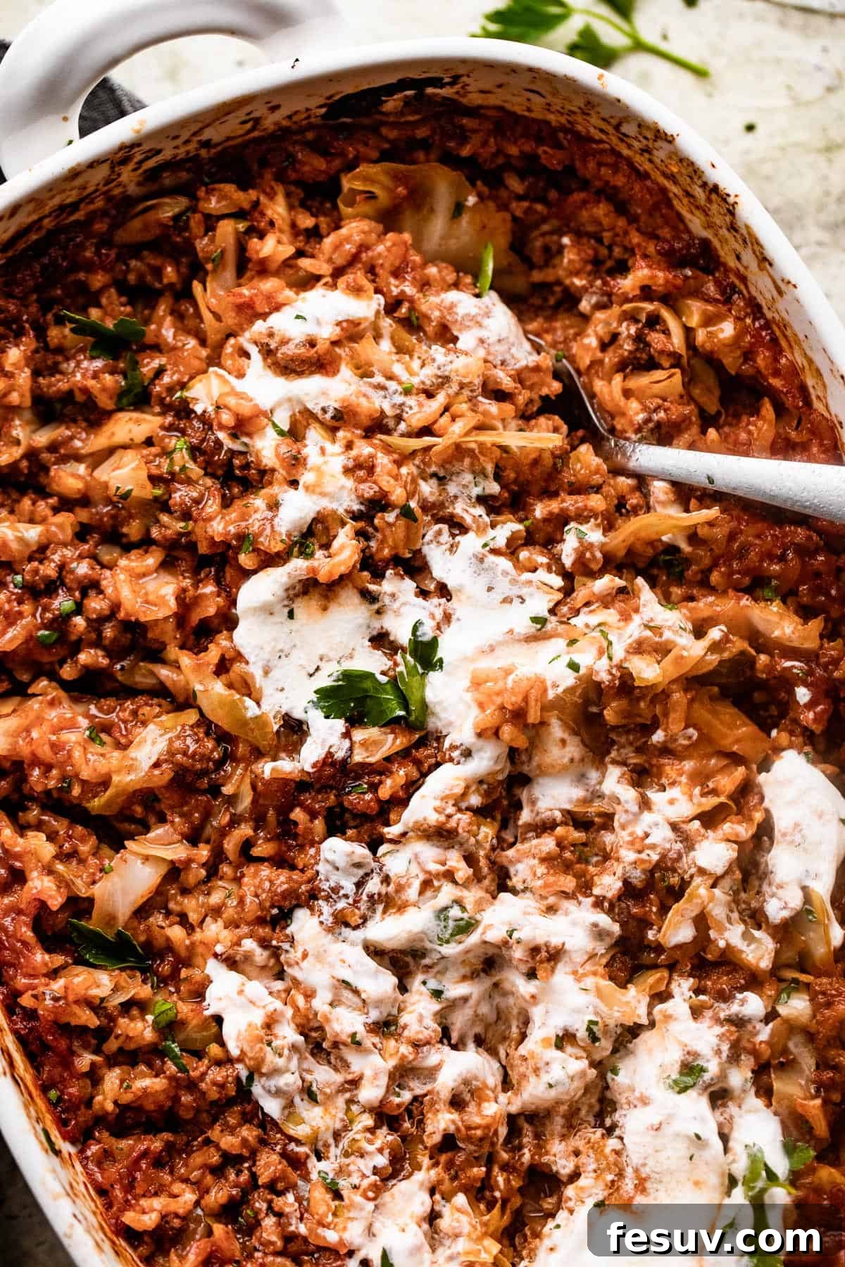 Hearty Cabbage Roll Casserole 2 overhead shot of Cabbage Roll Casserole in a white baking dish, and the casserole is smothered with sour cream on top.