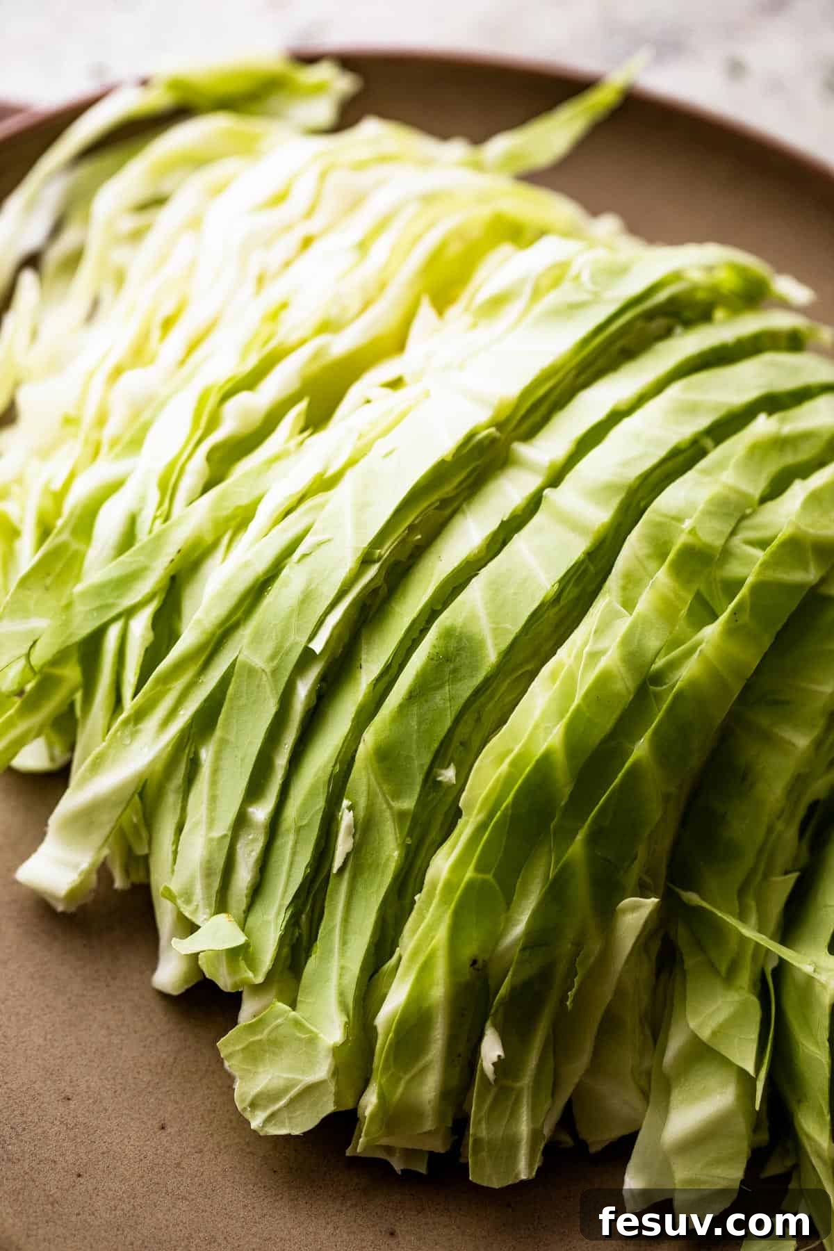 Hearty Cabbage Roll Casserole 4 sliced green cabbage on a brown plate.