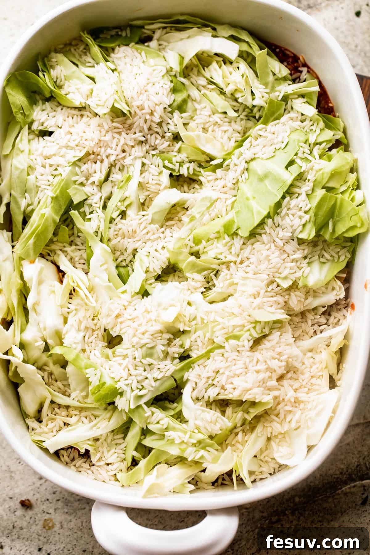 Hearty Cabbage Roll Casserole 6 overhead shot of chopped cabbage and dry rice inside a white baking dish