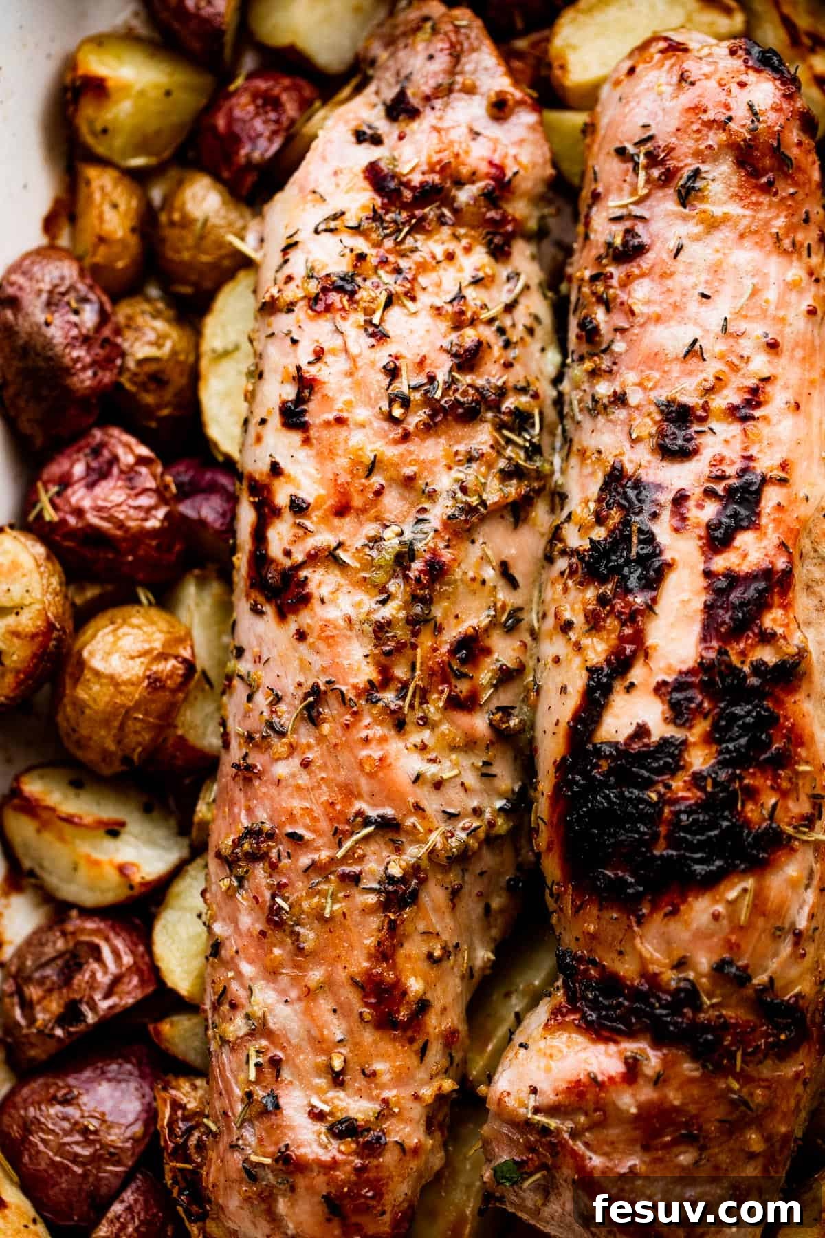 Herb-Crusted Pork Tenderloin with Golden Potatoes 6 Roasted pork tenderloins set on top of cooked baby potatoes, glistening with sauce and herbs