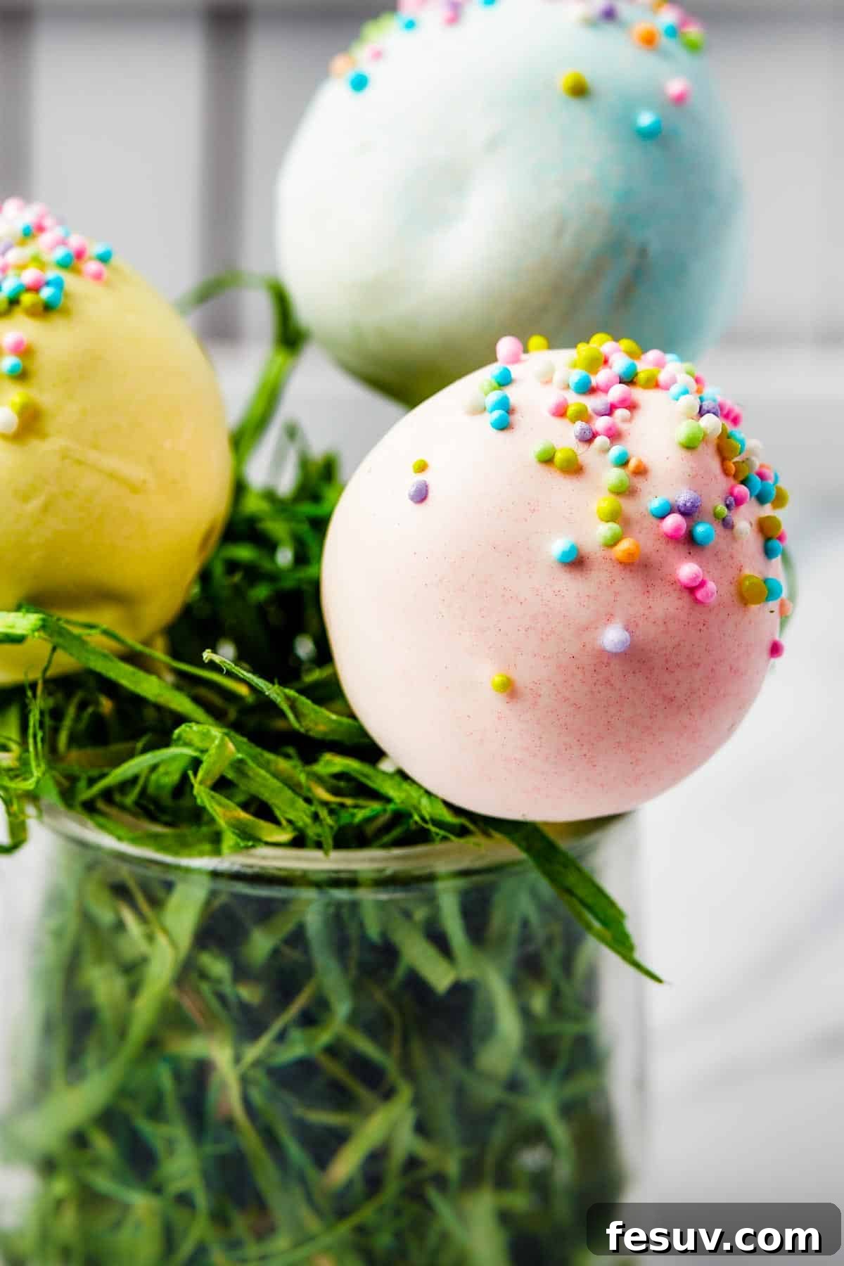 Pastel lollipops in a white basket filled with Easter grass.
