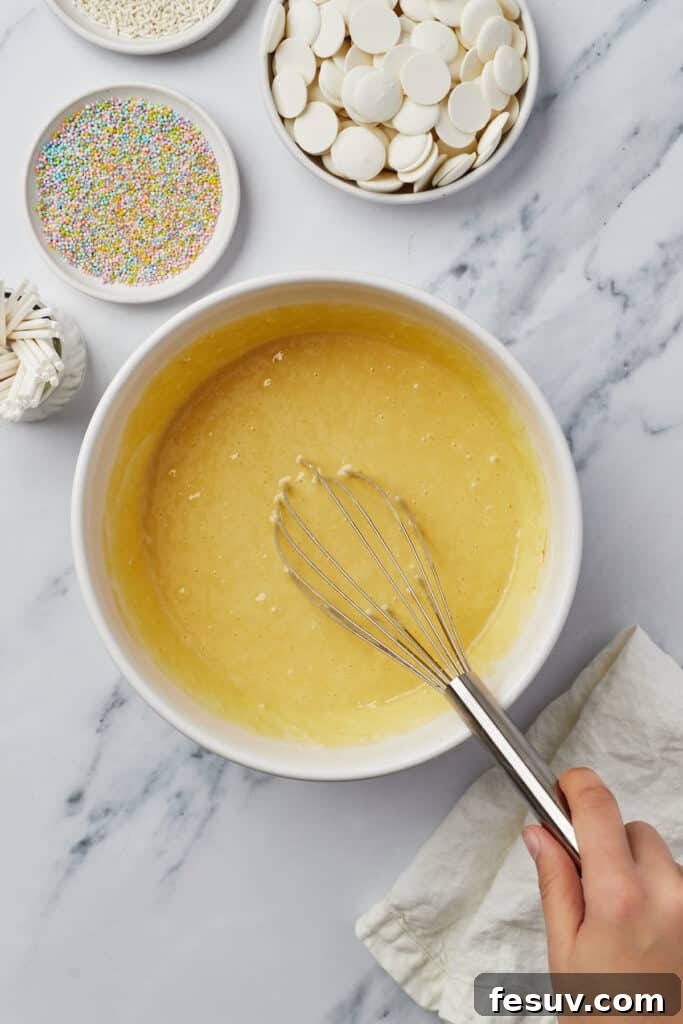 Yellow cake batter in a mixing bowl with a whisk.