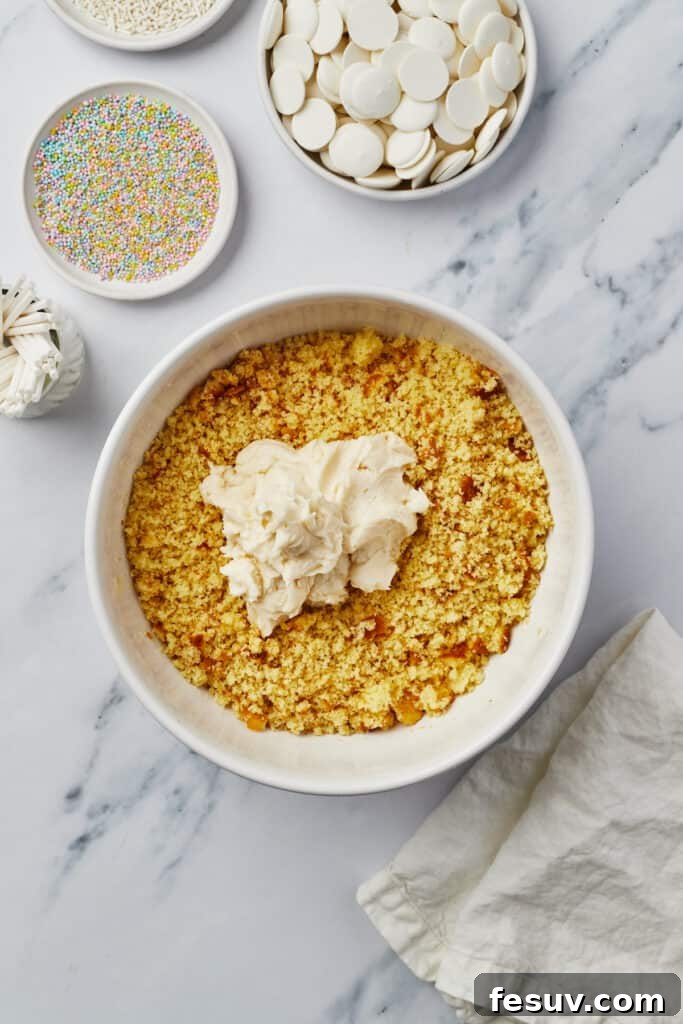 Cake crumbs and frosting in a mixing bowl.