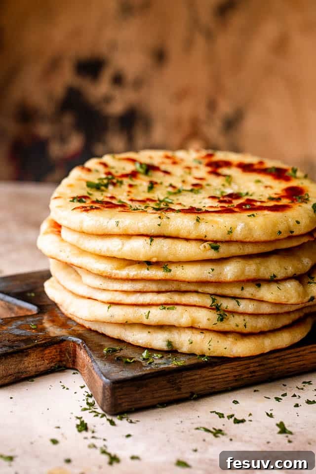 A beautiful stack of soft, fluffy homemade flatbreads arranged artfully on a rustic wooden board, ready to be enjoyed.