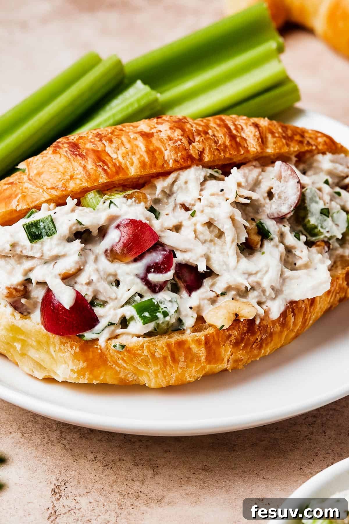 Chicken salad in a split croissant, showcasing its creamy texture and fresh ingredients.