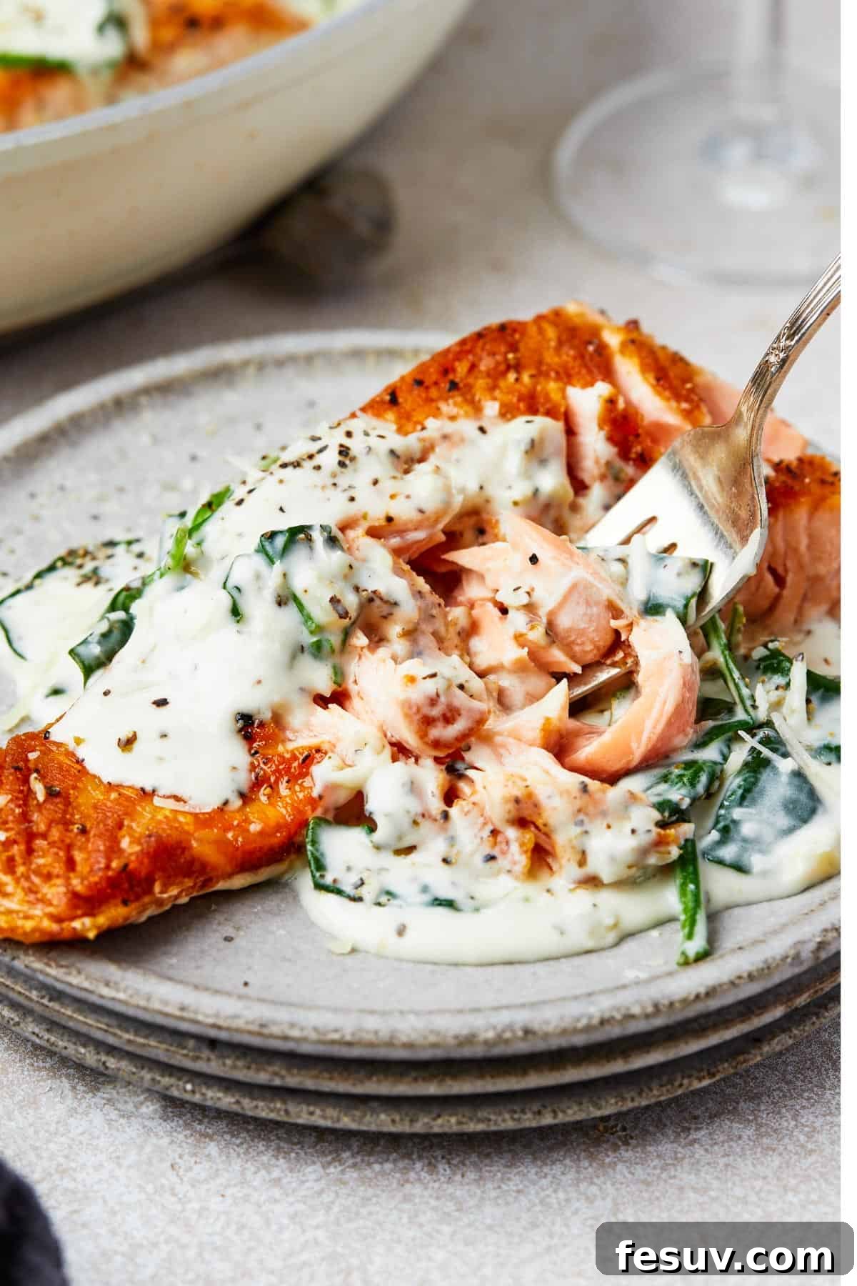 A serving of salmon Florentine, with a fork lifting a bite towards the camera, highlighting the delicious texture of the salmon and sauce.