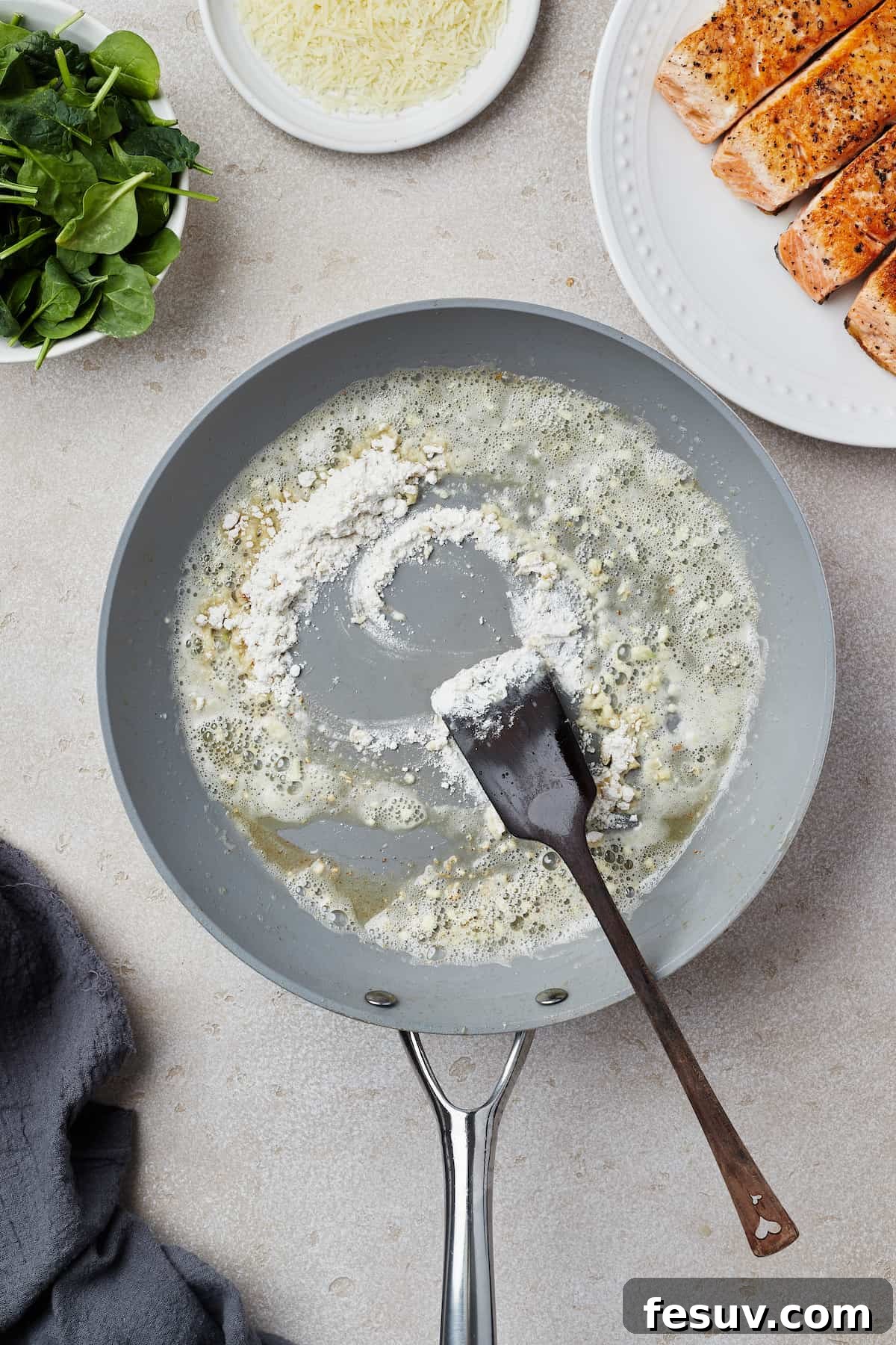 A skillet with melted butter, minced garlic, and flour cooking to form a roux for the sauce.