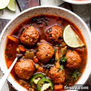Hearty Mexican Meatball Soup 7 overhead shot of two soup bowls filled with albondigas soup and garnished with limes and sliced jalapenos.