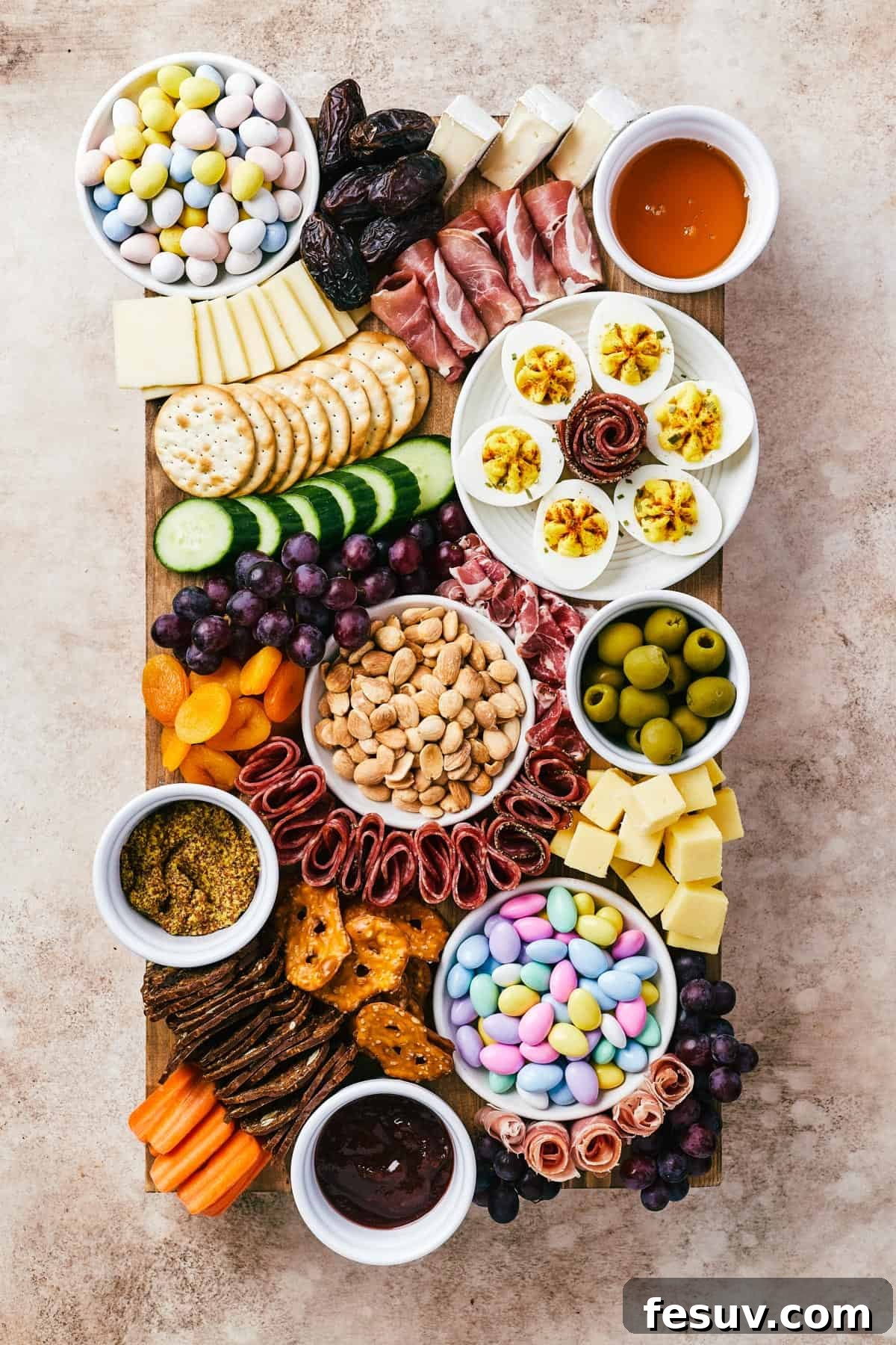 Craft the Perfect Easter Charcuterie Board 2 A beautifully arranged wooden charcuterie board showcasing a variety of meats, cheeses, crackers, olives, colorful fruits, and fresh vegetables, perfect for Easter celebrations.