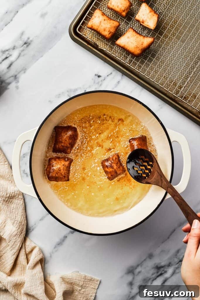 French Quarter Powdery Delights 8 Browned, fried squares of dough in a Dutch oven partially filled with hot oil.