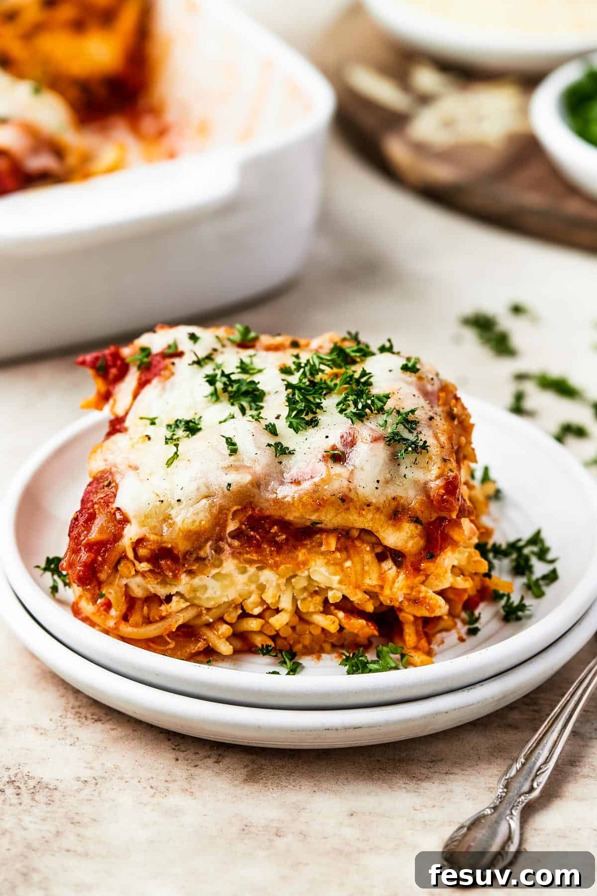 Irresistible Baked Spaghetti Delight 3 A perfectly portioned square of baked spaghetti casserole, served on a white plate, ready to be enjoyed.