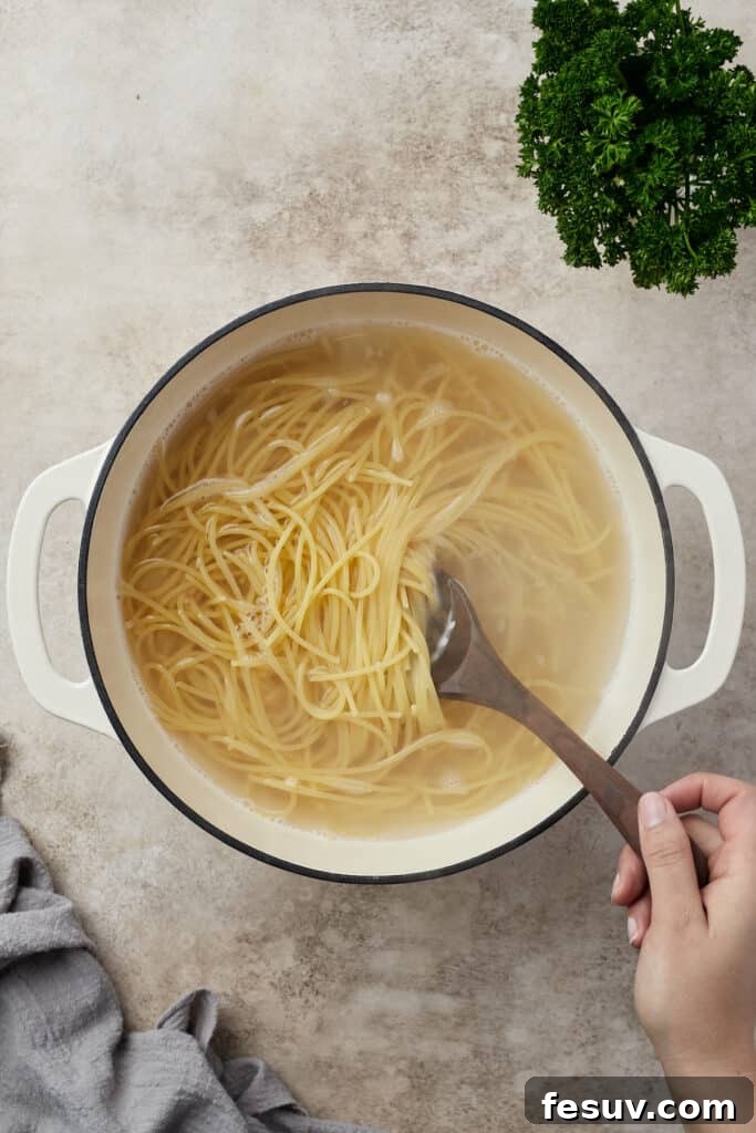 Irresistible Baked Spaghetti Delight 5 Spaghetti strands boiling vigorously in a large Dutch oven filled with salted water.