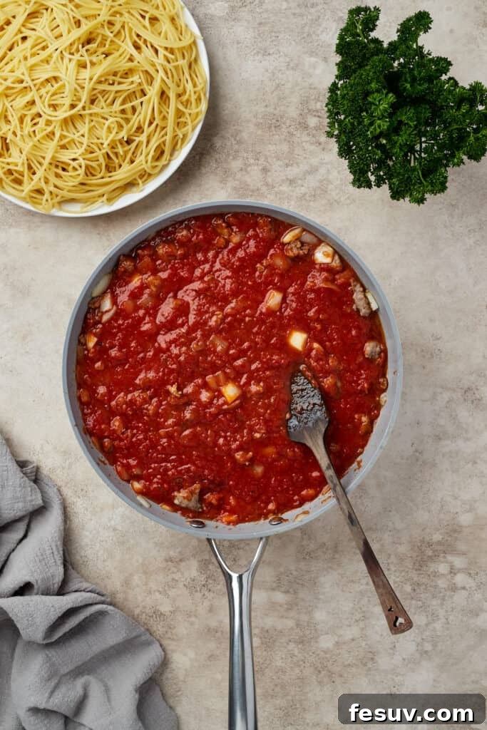 Irresistible Baked Spaghetti Delight 7 Rich meat sauce, made with Italian sausage, onions, garlic, and marinara, simmering gently in a skillet.