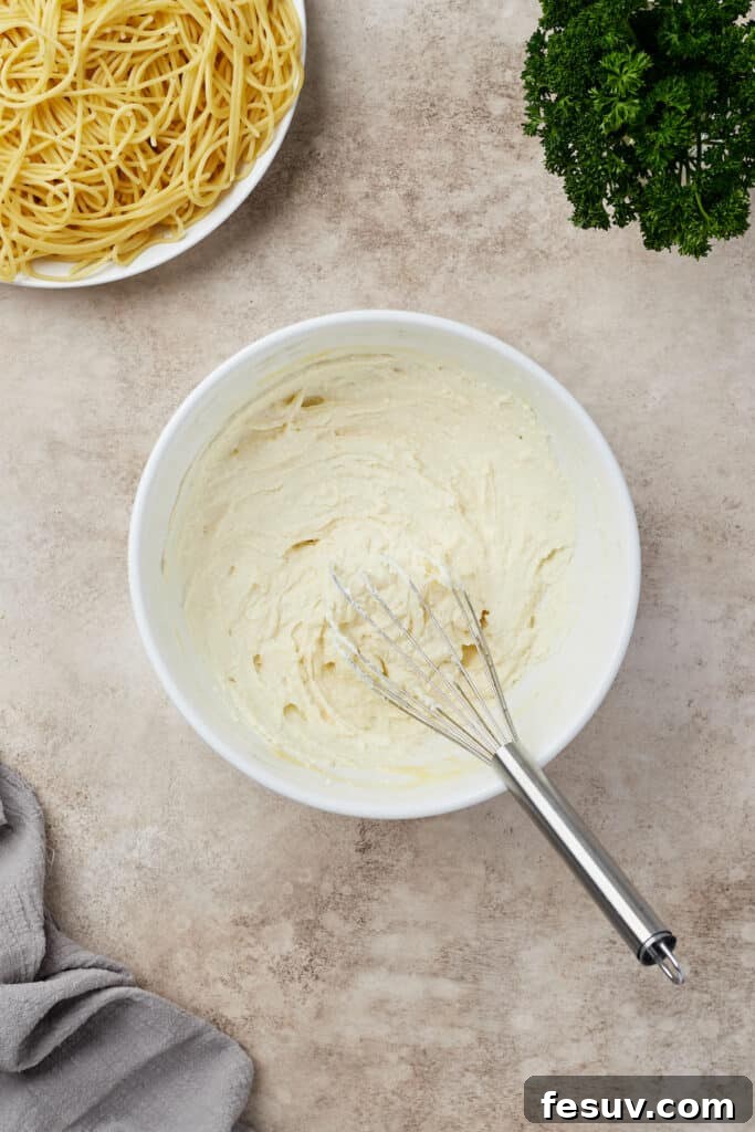 Irresistible Baked Spaghetti Delight 8 Ricotta cheese and an egg whisked until smooth and creamy in a glass mixing bowl.