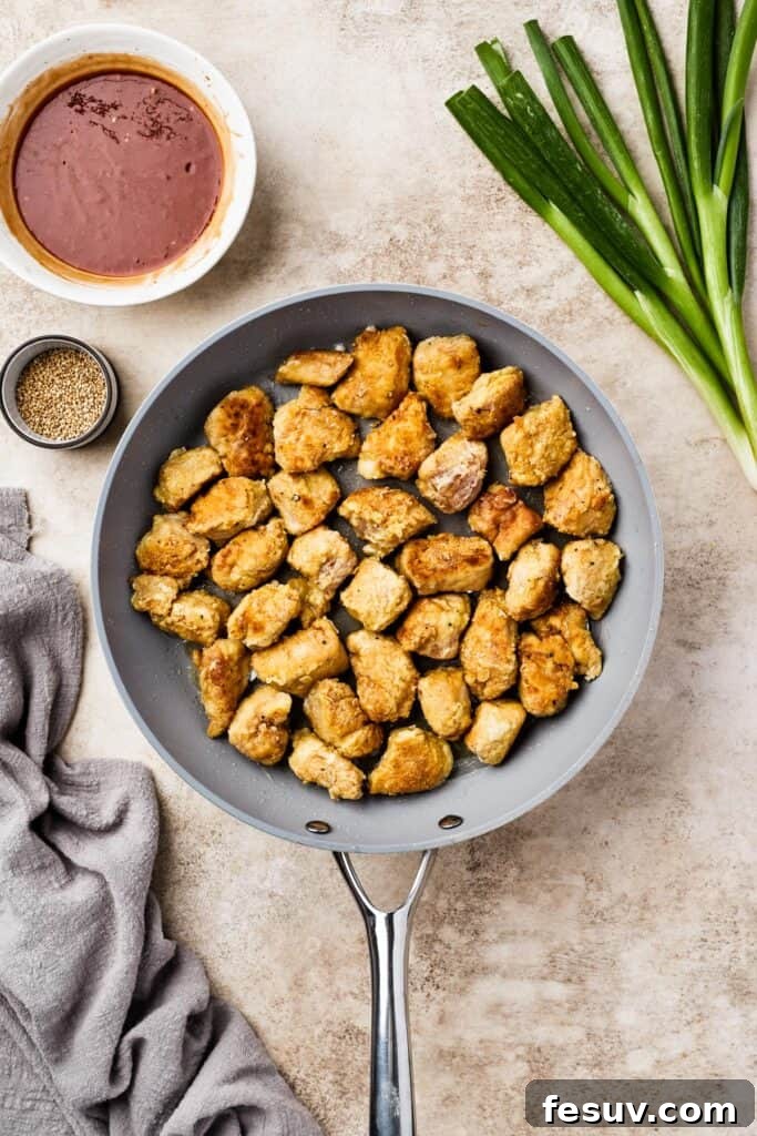 A pan filled with golden-brown, perfectly fried chicken pieces, ready for the sweet and sour sauce.