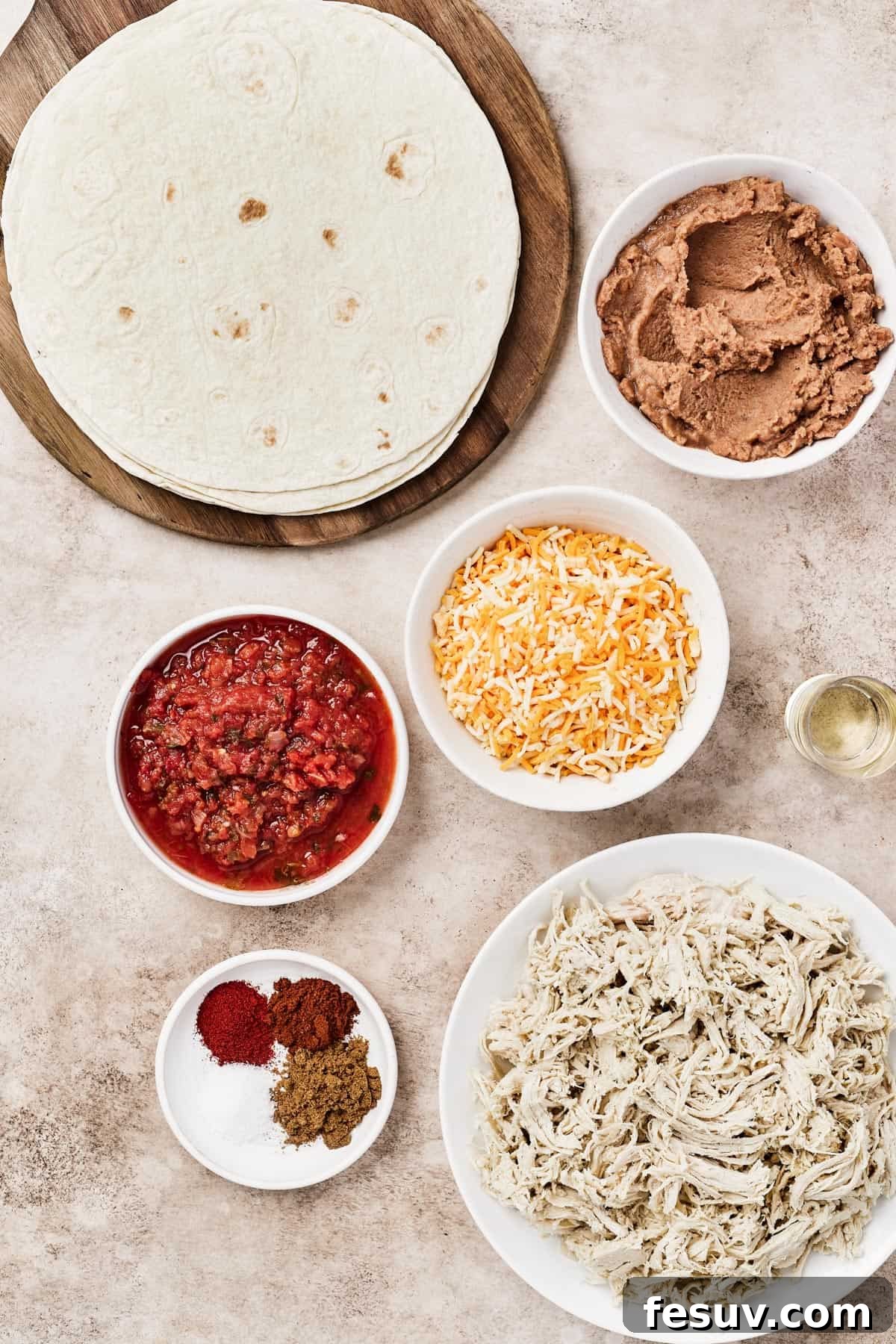 From top left: Tortillas, refried beans, salsa, shredded cheese, oil, spices, shredded chicken.