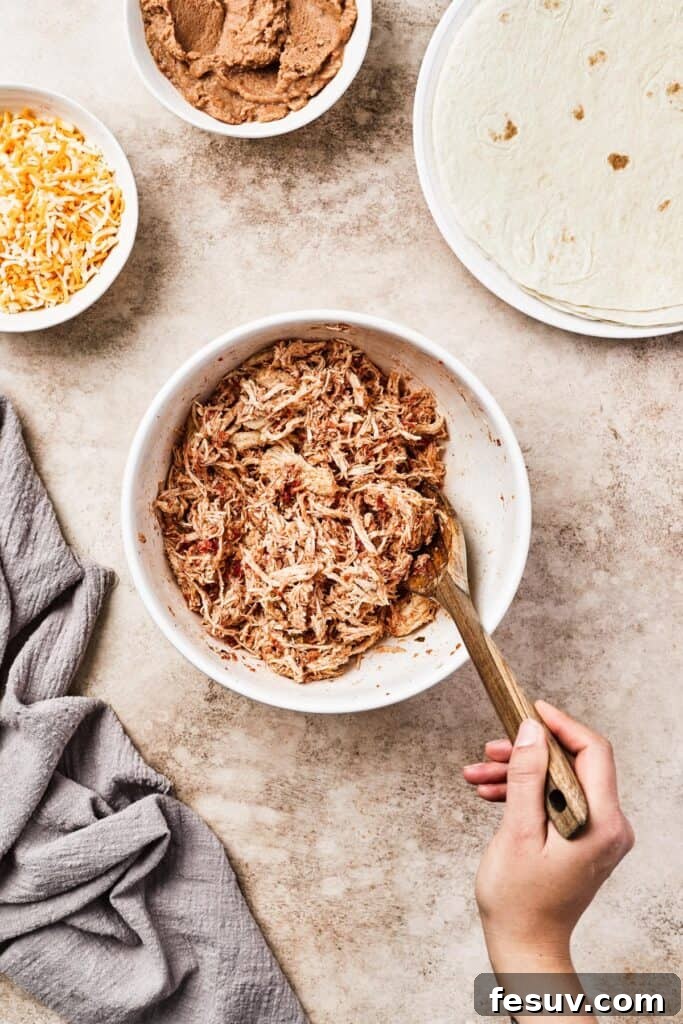 Shredded chicken mixed with salsa and spices in a white bowl.