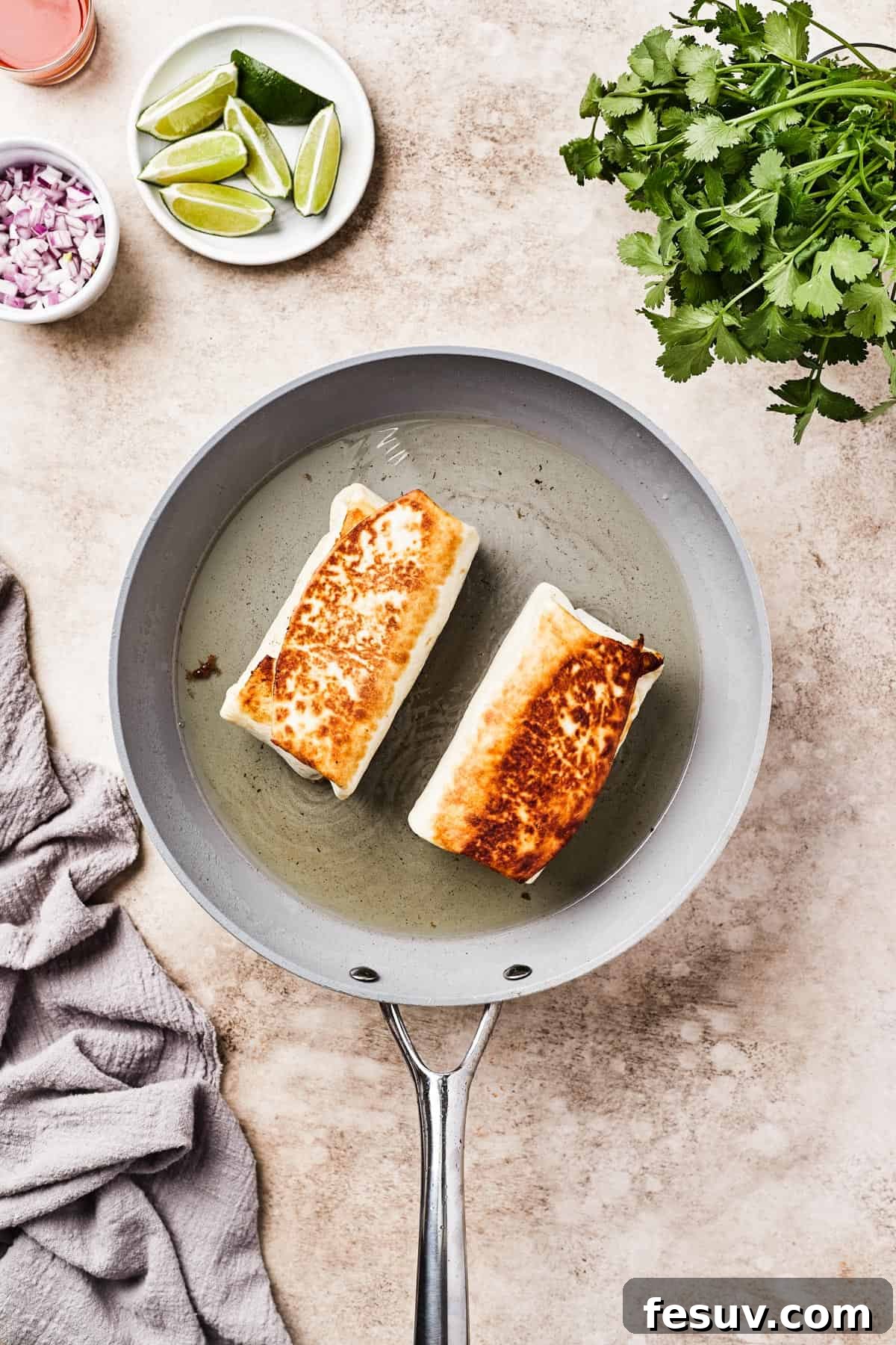 Fried burritos in a skillet with oil.