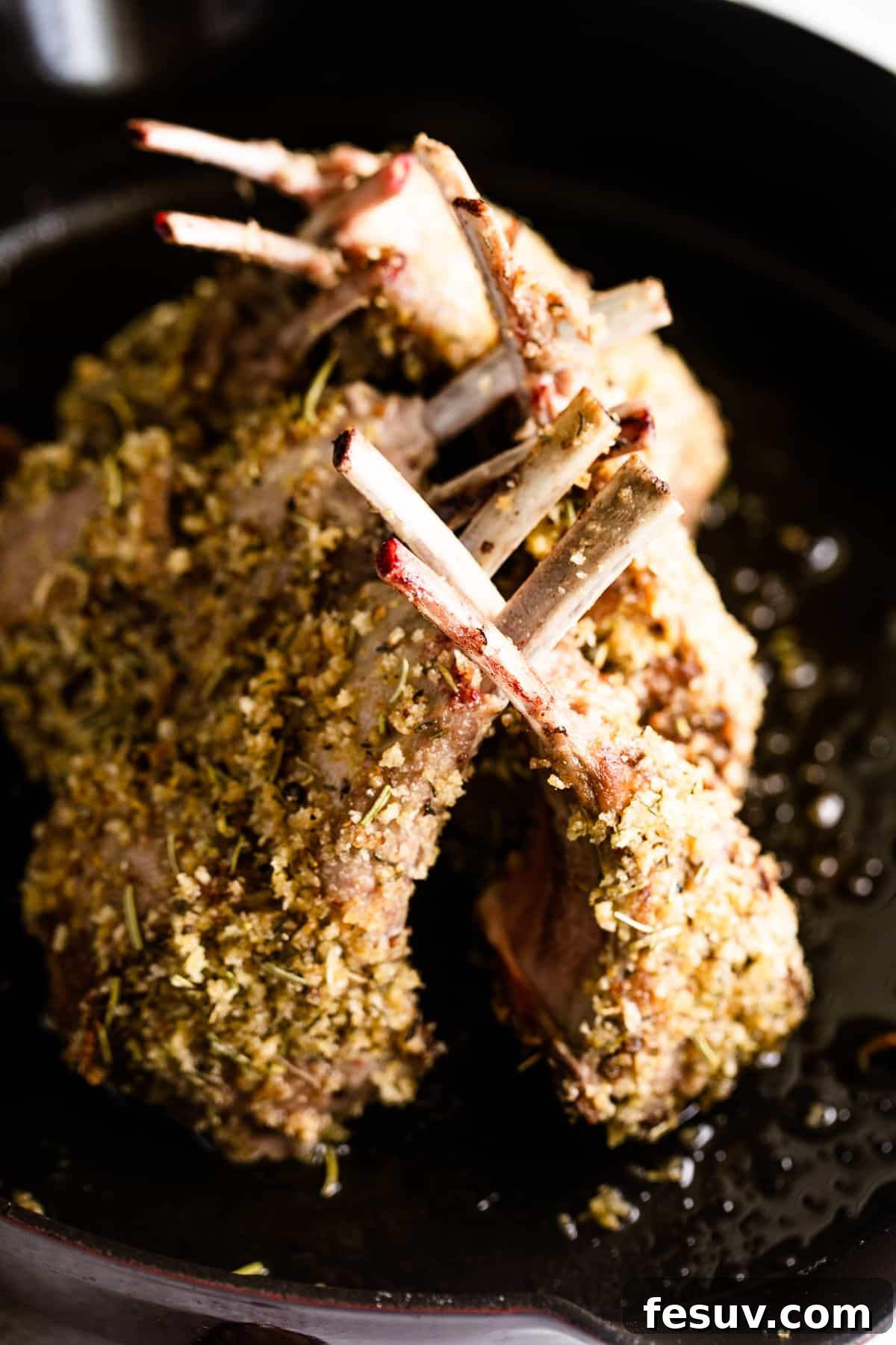 Elegant Herb-Crusted Lamb Rack 4 A pristine, cooked frenched rack of lamb, perfectly roasted and ready for carving, showcasing its golden crust and exposed rib bones.