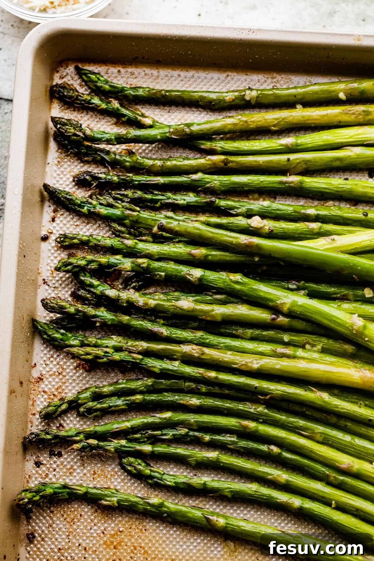 Overhead shot of freshly roasted asparagus spears glistening with garlic butter on a baking sheet.