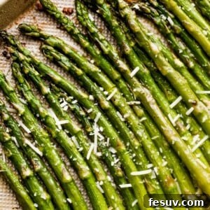 Parmesan-topped roasted asparagus spears arranged on a gold-colored baking sheet, ready to be served.
